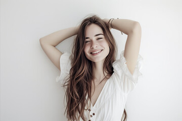 Fototapeta premium A woman with long brown hair is smiling and posing for a picture. She is wearing a white dress and a necklace