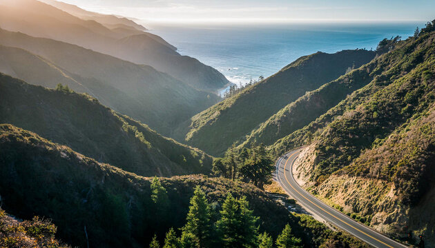 A road winding it's way through a valley and heading towards the coast in the afternoon with a view of the ocean