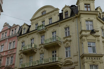 This charming historic building boasts a striking yellow facade adorned with intricate architectural details, featuring lovely balconies that enhance its appeal amid a vibrant urban setting