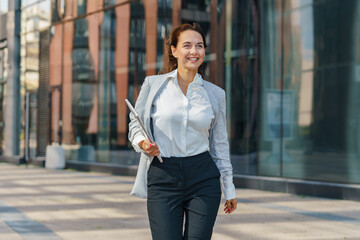 Professional Woman in Business Attire Walking Confidently Outside a Modern Office Building During Daytime