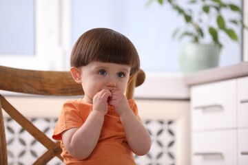 Little boy playing on chair in kitchen. Dangerous situation