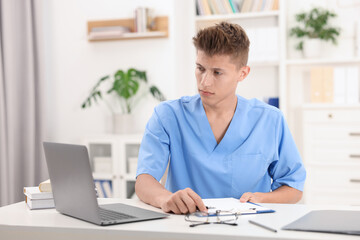 Fototapeta premium Medical student in uniform studying at table indoors