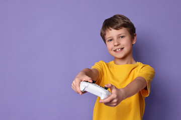 Happy little boy playing video game with controller on purple background. Space for text © New Africa