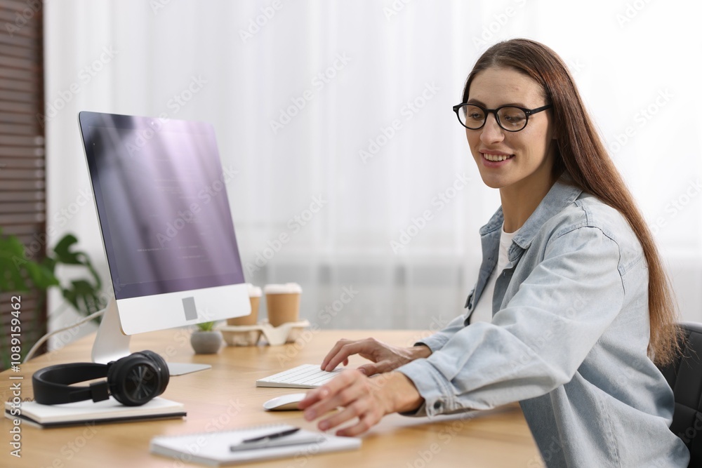 Poster programmer working on computer at wooden desk indoors