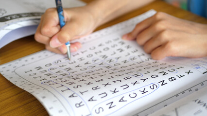 Close up of a kid solving a word search puzzle