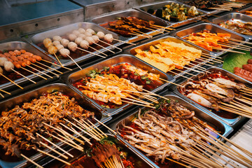 Chinese snacks including pork, meatballs, intestines and seafood brochettes displayed in a popular street market at Nanjing Road at night, Shanghai, China
