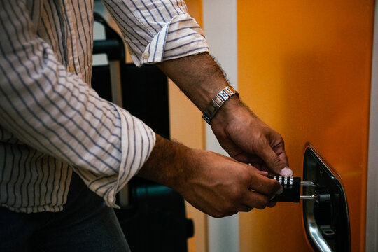 Hands of man opening a locker in a warehouse to store his luggage, Shanghai, China - Powered by Adobe