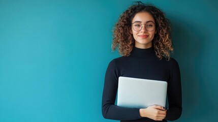 Young happy latin woman pointing at laptop isolated on blue background. Smiling female model holding computer presenting advertising job search or ecommerce shopping website.
