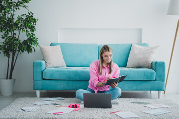 Young woman studying at home with a laptop, enjoying leisure time in a bright living room with natural daylight