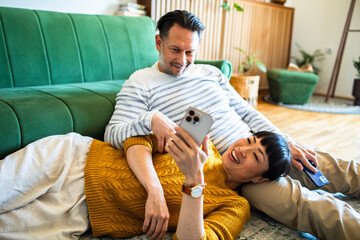Happy couple relaxing on the couch and sharing a moment while looking at a smartphone