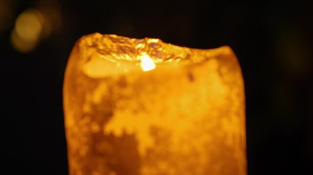 A glowing candle flickering gently on a cozy evening setting in 4K slow motion 60fps