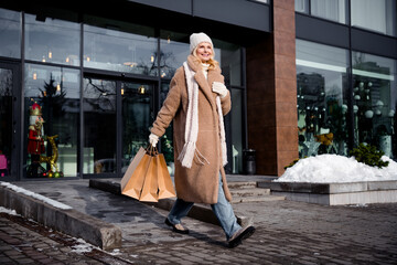 Photo of cheerful positive good mood retired woman wearing warm coat hat carrying packages preparing gifts