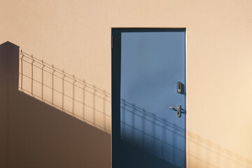 Porte métal bleue sécurisée par digicode sur mur crépis ocre d'un bâtiment industriel au...