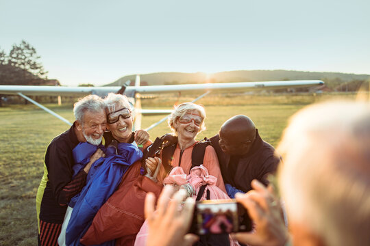 Diverse senior friends taking group photo after skydiving
