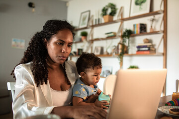 Busy mom working with laptop at home with toddler