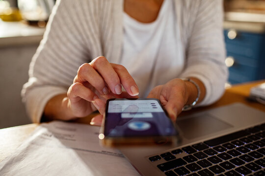Close up of woman hands using smartphone for online banking at home