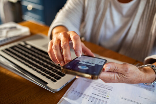 Close up of woman hands using smartphone for online banking at home