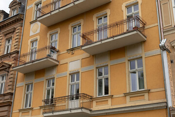 This charming yellow apartment building features an appealing design with attractive balconies and large windows, embodying the essence of urban architecture in a vibrant, bustling city
