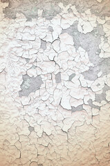 Peeling paint of beige color on the old rough concrete surface