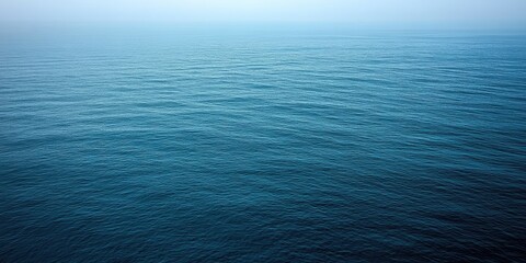 Obraz premium Under a muted winter sky, endless waves ebb and flow, reflecting various shades of blue across the water. The calmness brings a serene atmosphere for winter reflections and peace