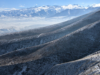 Winter view of landcape. Snow-capped mountains in the clouds  and haze against a blue sky. Vivid...