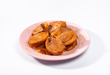 Traditional brazilian christmas Rabanadas with egg yolk crea and cinnamon, Spanish Torrijas on soft pink plate isolated on white background.