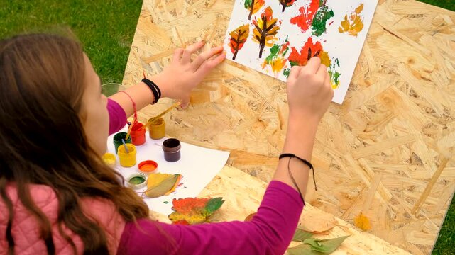 Child drawing autumn leaves. Selective focus.