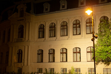 The mesmerizing night view of the elegant and historic building facade, beautifully illuminated by a glowing street lamp, showcases its intricate architectural details and creates a unique ambiance