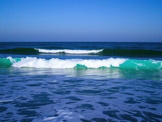 Fototapeta premium Ocean waves at night with a turquoise green hue rolling towards the shore under a light blue sky, blue, serene, oceanic