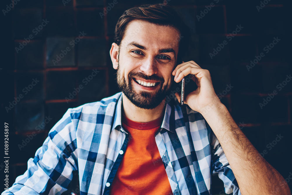 Aufkleber portrait of successful bearded student smiling at camera while calling on smartphone and making note