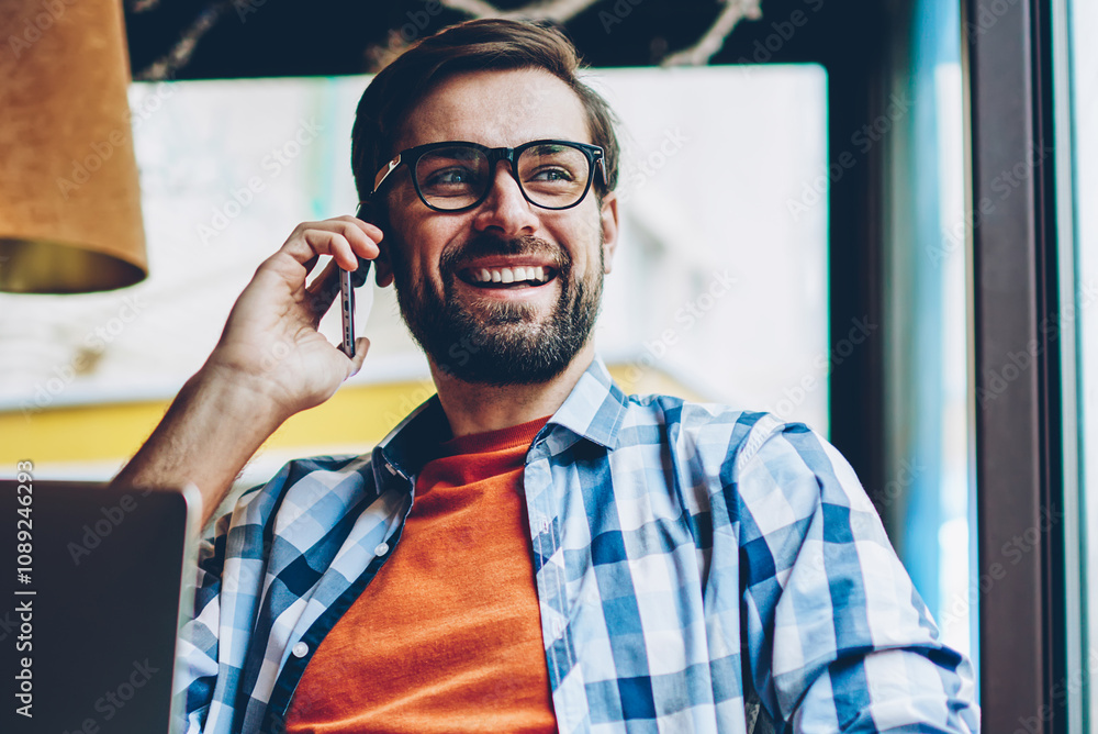 Aufkleber cheerful bearded hipster guy calling on smartphone and laughing during mobile conversation looking o