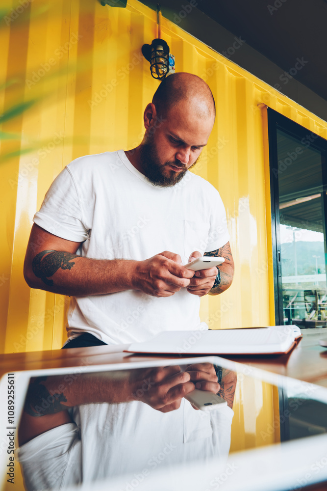 Poster hipster guy chatting in social networks via mobile phone sending text message, young millennial male