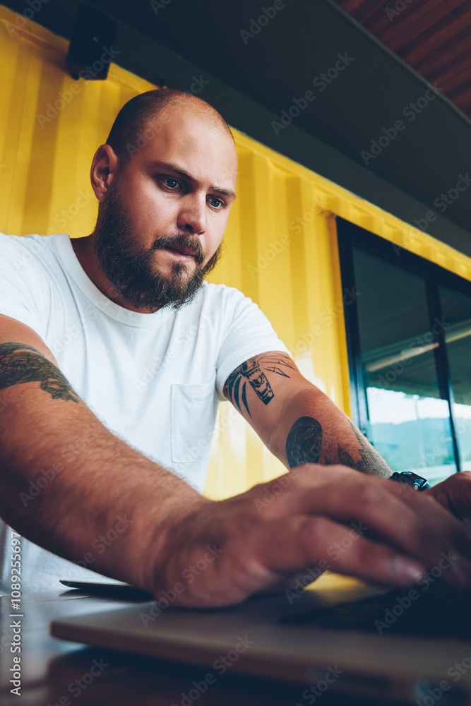 Poster worried caucasian hipster guy concentrated on playing video game on laptop computer, serious millenn