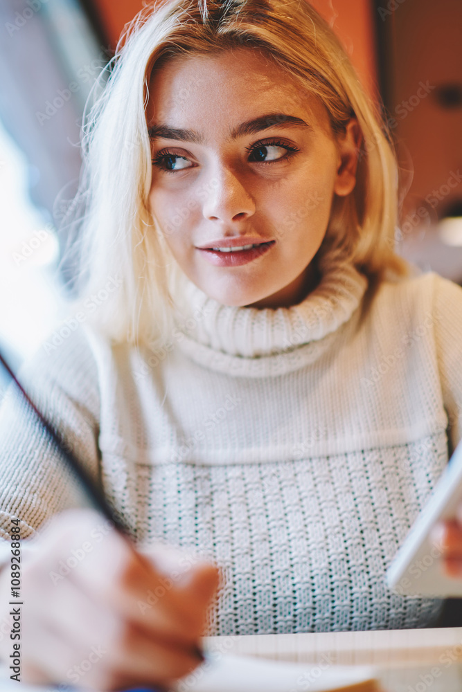 Poster clever female student doing homework task in cafe interior holding smartphone for networking,creativ