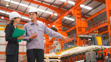 A male expertise engineering is explaining about the quality of metal sheet machine of industry to female inspector and Mechanic or technician in manufacturing or factory, Business's safety check.