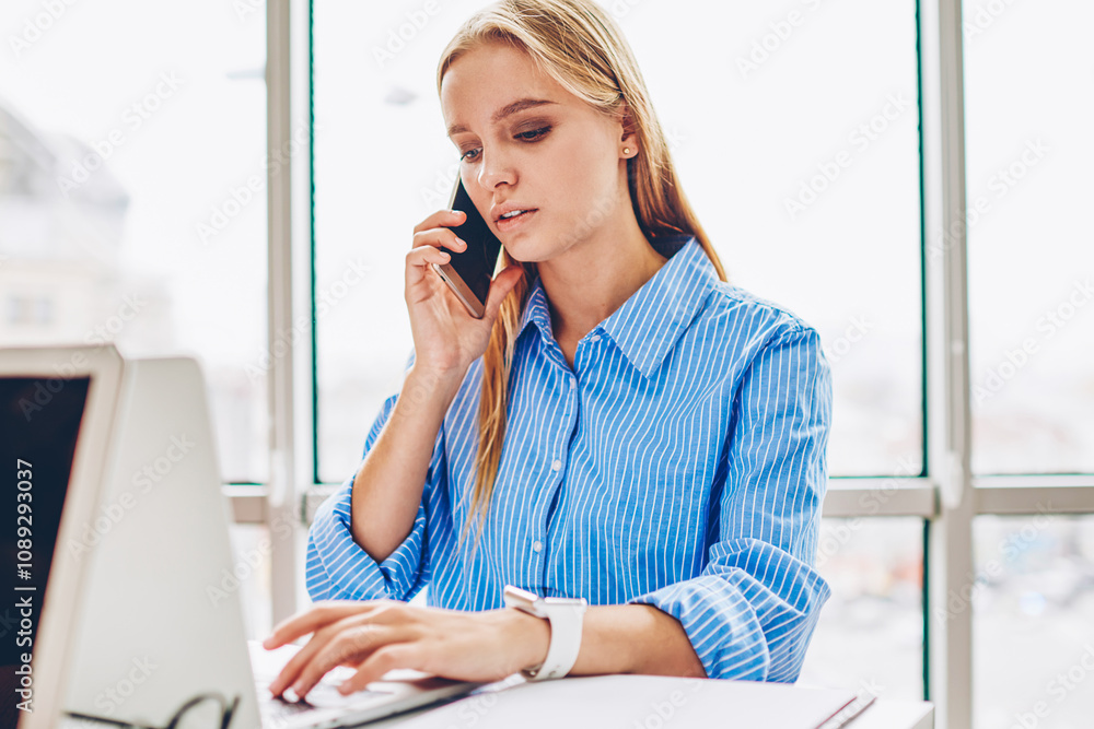 Poster concentrated female manager having mobile phone conversation about business checking report on netbo