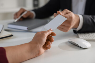Obraz premium Woman giving business card to man at table in office, closeup. Mockup for design