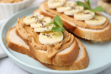 Tasty sandwiches with peanut butter, banana, chia seeds and mint on table, closeup