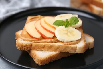 Tasty sandwich with peanut butter, apple, banana and mint on table, closeup