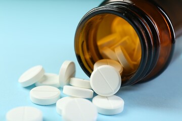 Bottle of antibiotic pills on light blue background, closeup