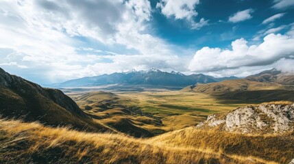 Obraz premium Breathtaking panorama of expansive wilderness featuring rolling hills, dramatic mountains, lush valleys, and a dynamic sky filled with clouds.