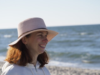 Woman in a hat on the beach with a view of the sea on a sunny day