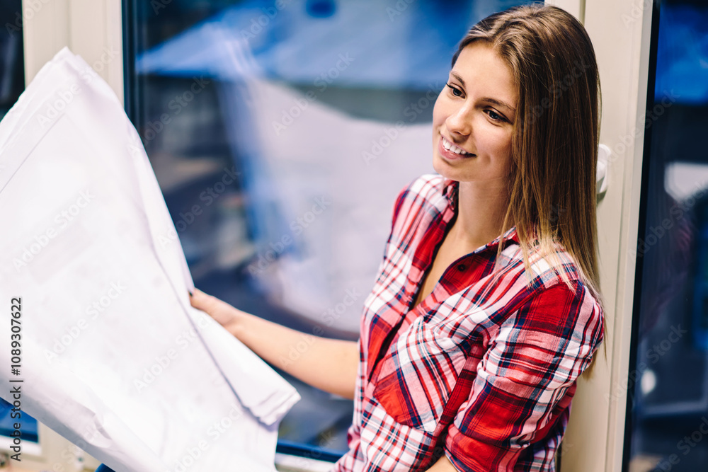 Poster smiling woman holding papers with drawings satisfied with completing blueprint before deadline sitti