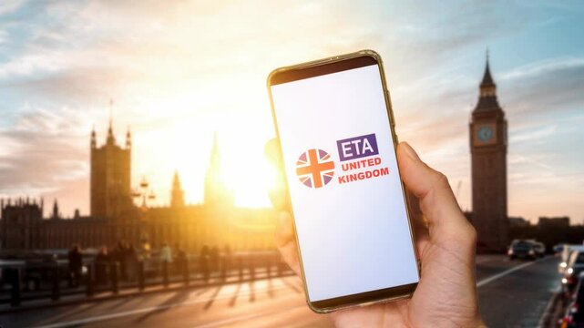A smartphone displaying the UK Electronic Travel Authorization or ETA app, held in front of London's iconic Big Ben and Parliament. In 2025 all visitors will need an ETA to travel to the UK
