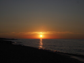 Sunset over the sea with reflection on water and golden clouds in the sky