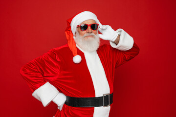 Photo of bearded Santa Claus wearing hat, glasses,posing empty space christmas ad isolated on vivid red color background. Christmas promotion, New Year concept