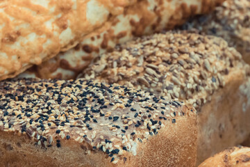 Fresh traditional loaves of wheat or rye bread with grains on stall or in bakery