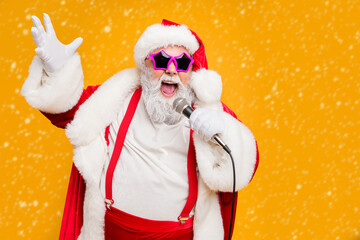 Portrait of fat big belly crazy funky santa claus hold microphones have live x-mas performance sing carols on christmas night wear red hat headwear trendy suspenders isolated yellow color background