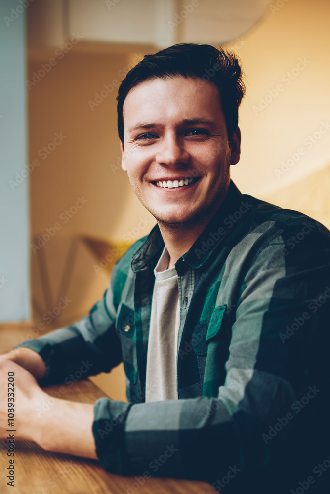 Poster portrait of cheerful hipster guy in casual wear enjoying coffee break chatting via telephone, happy 