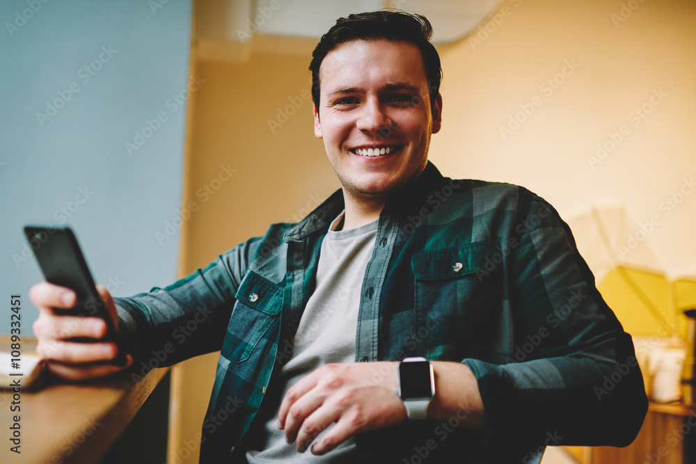 Poster portrait of cheerful teen male holding cellular satisfied with wireless connection for chatting and 